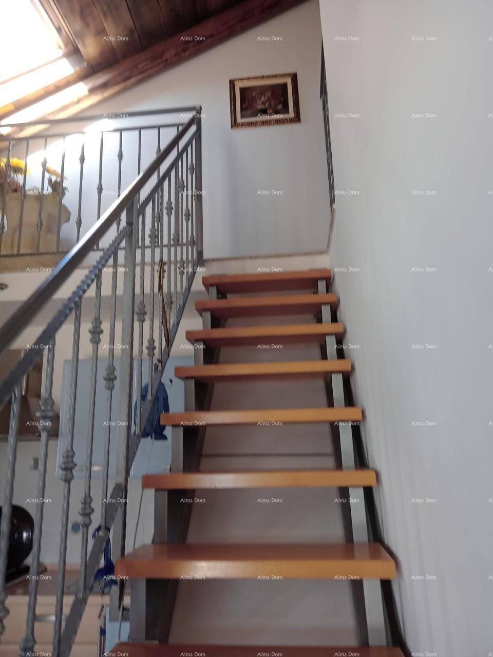 Holztreppe mit Metallgeländer, die zu den oberen Etagen des Hauses führt.