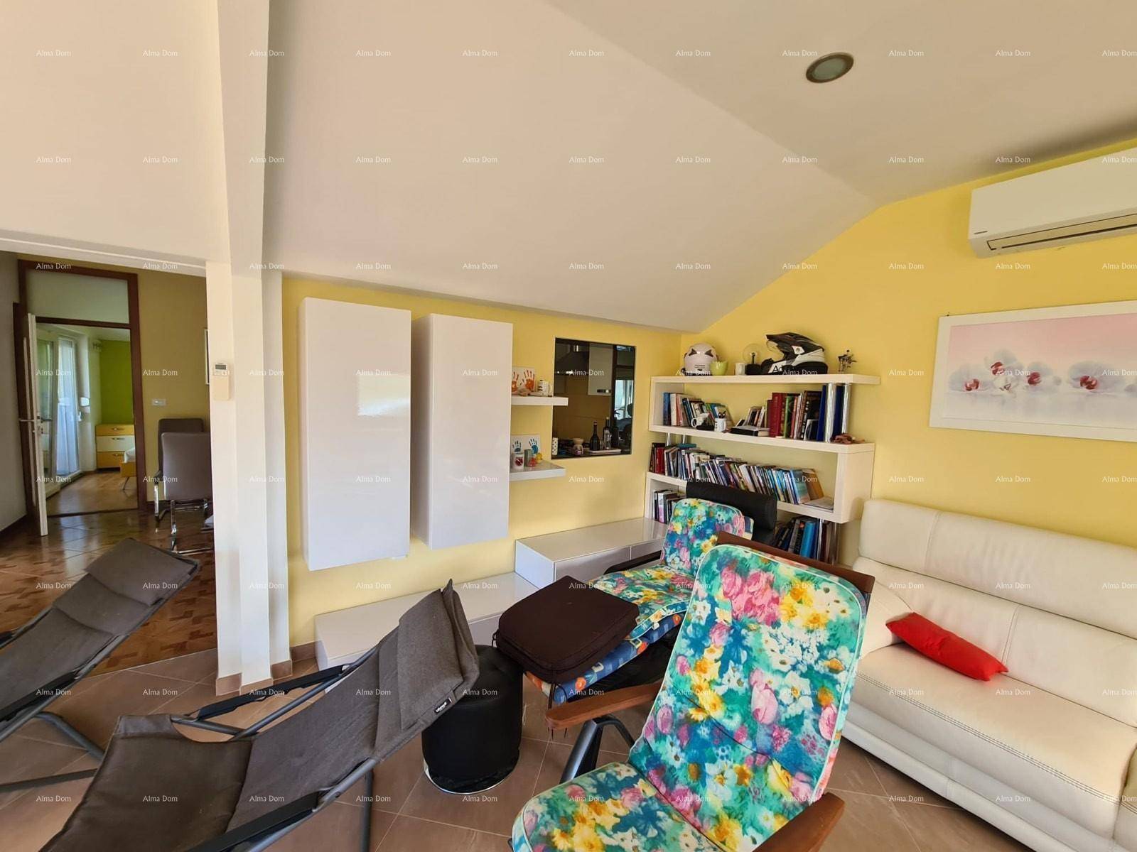 Gemütliches Wohnzimmer mit farbenfrohen Sesseln, weißem Sofa und einem Bücherregal an der Wand.