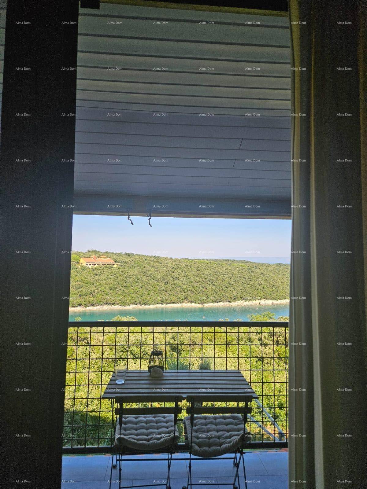 Blick vom Innenraum auf einen möblierten Balkon mit Meer- und Grünblick.