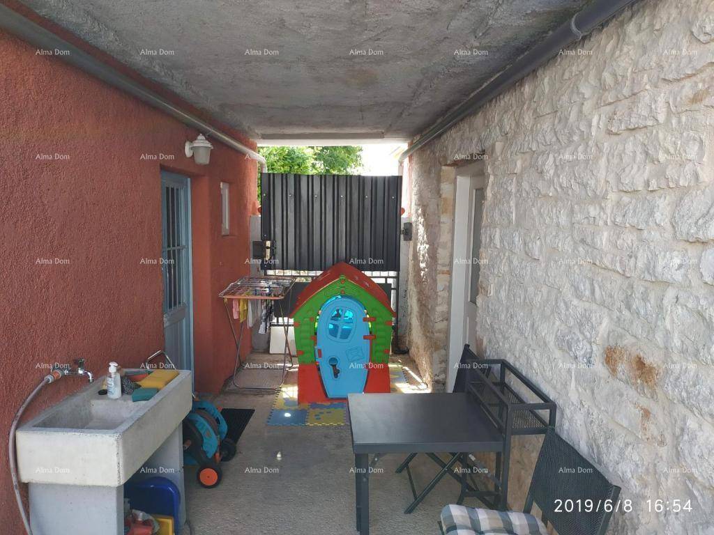 Überdachter Außenbereich mit Kinderspielhaus, Tisch und Waschbecken, ideal für Familien.