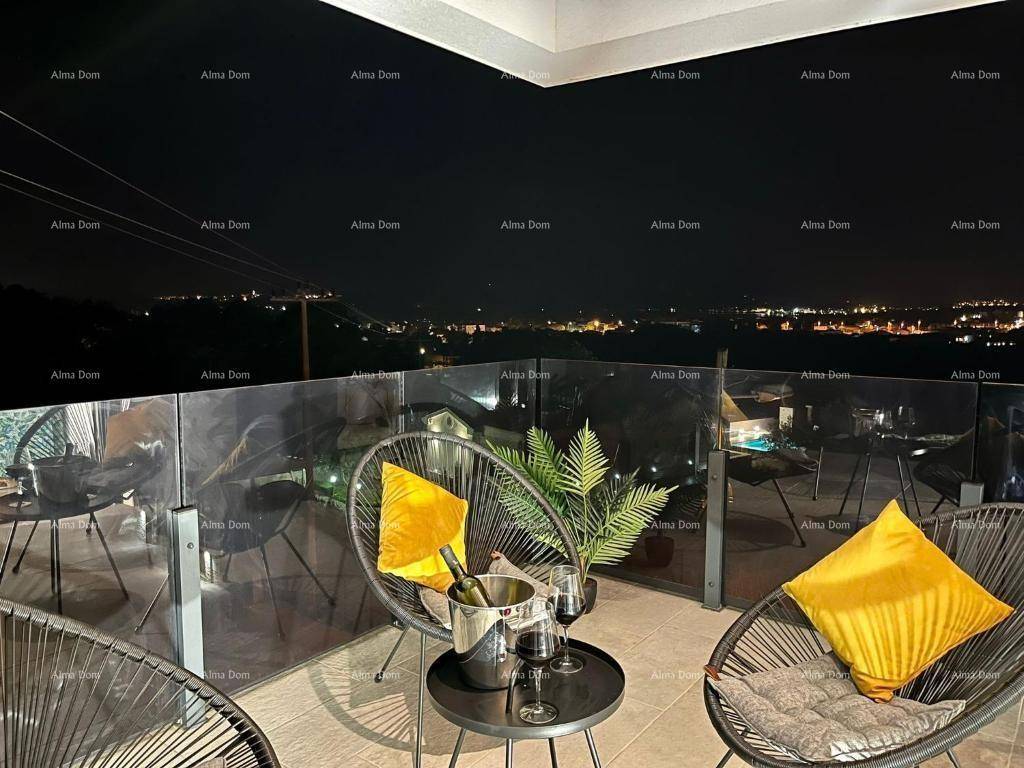 Beleuchteter Balkon bei Nacht mit Sitzgelegenheiten und Stadtblick.