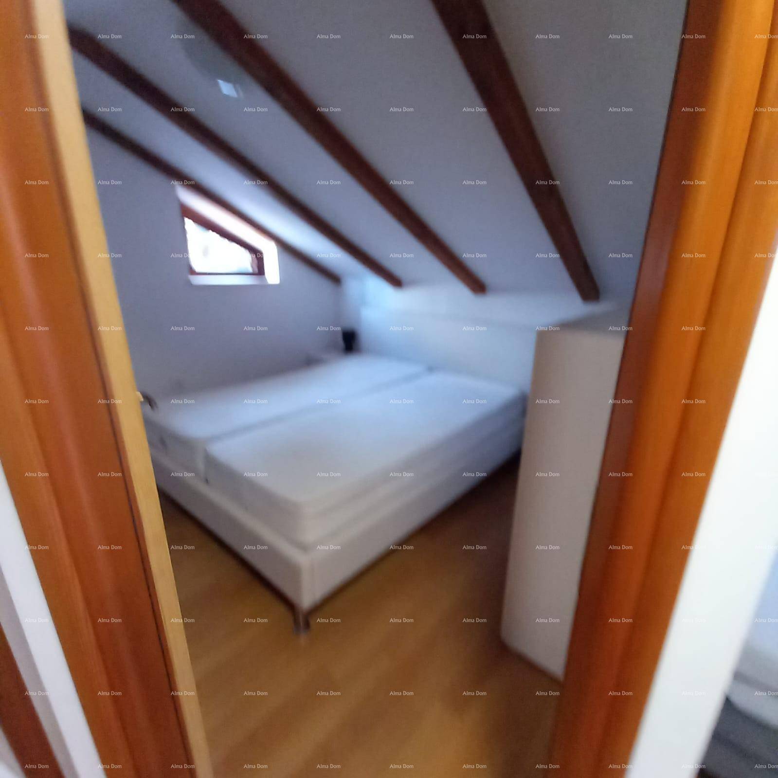 Schlafzimmer mit Doppelbett unter Dachschrägen, Holzbalken und Dachfenster.