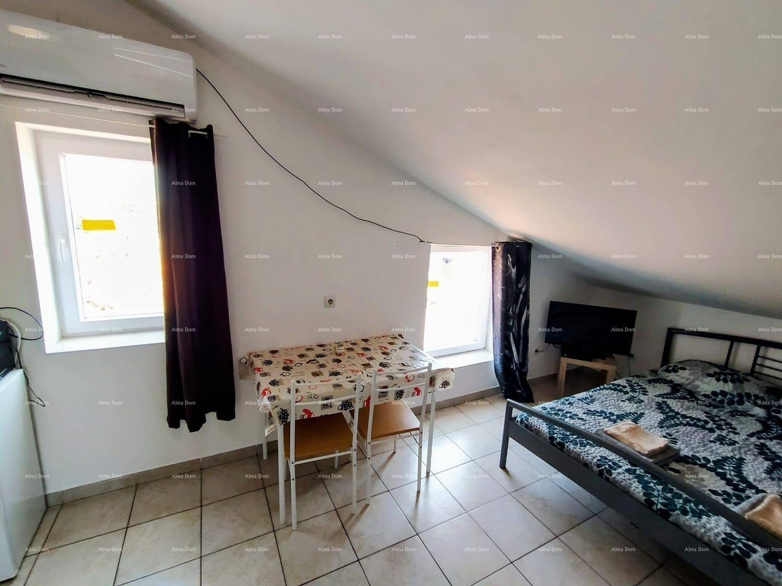 Helles Studio-Apartment mit Bett, Essbereich und Klimaanlage unter dem Dach.