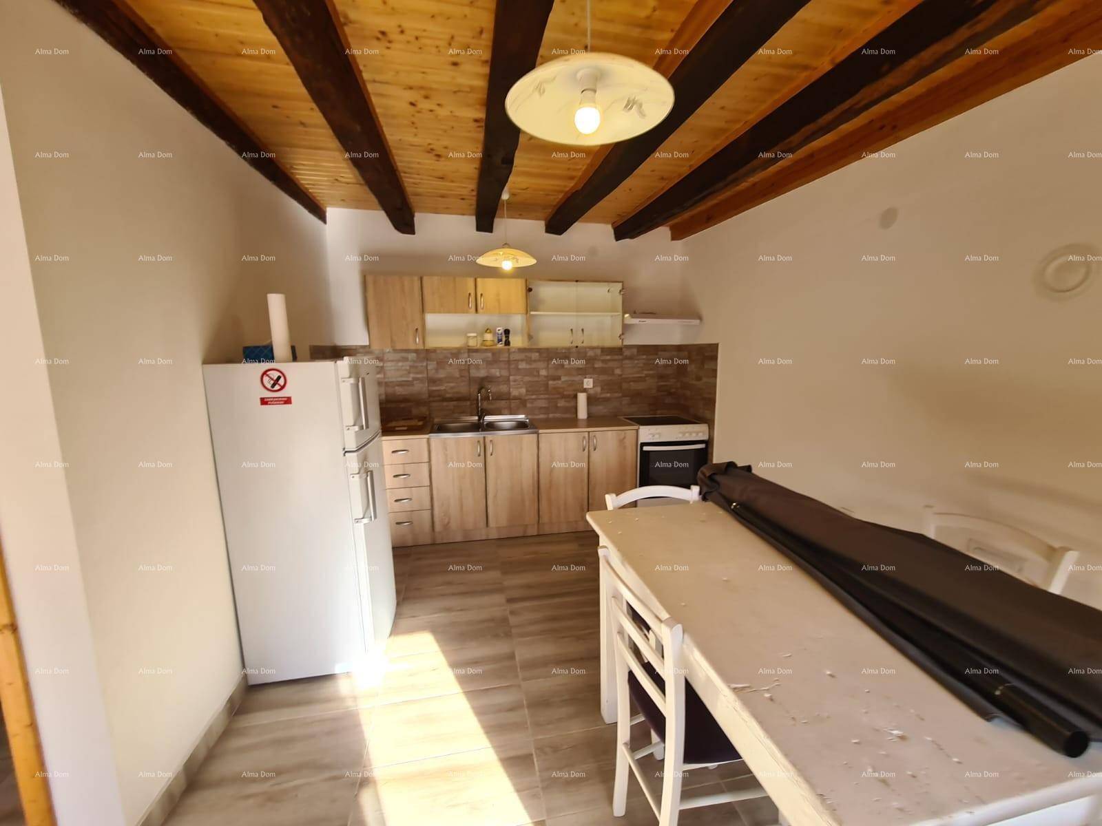 Einfache Küche mit Essbereich, Kühlschrank und Holzbalkendecke, funktional eingerichtet.