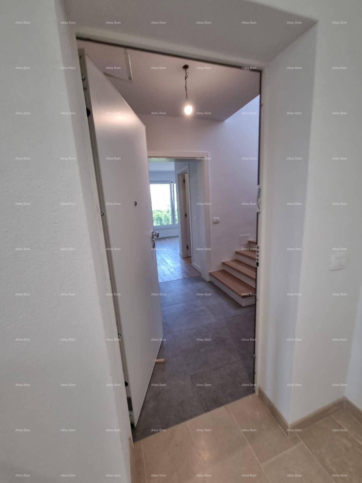 Eingangsbereich mit offener Tür, hellem Fliesenboden und Blick in den dahinterliegenden Wohnbereich.