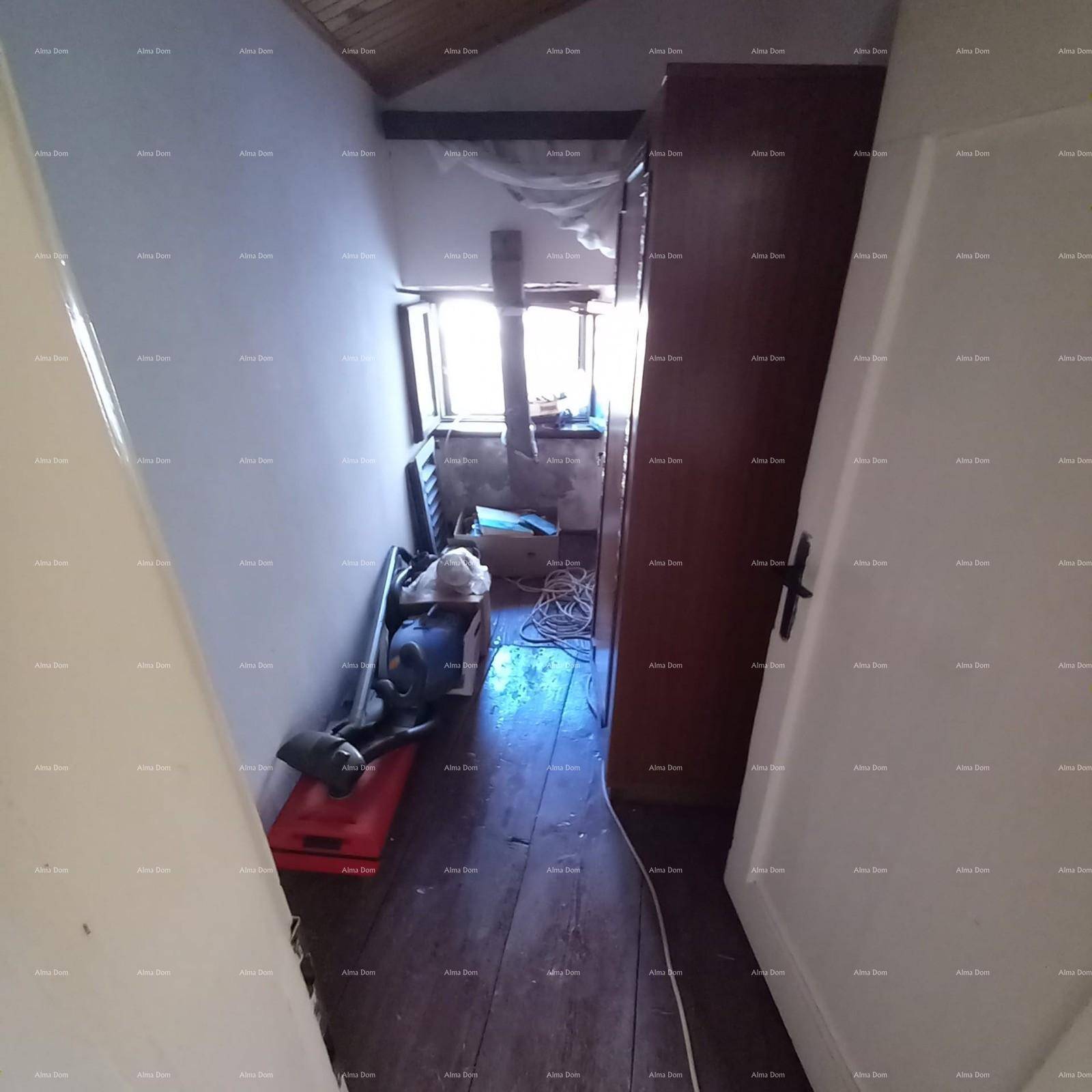 Schmaler Raum mit Holzdielenboden, Fenster und verschiedenen Gegenständen.