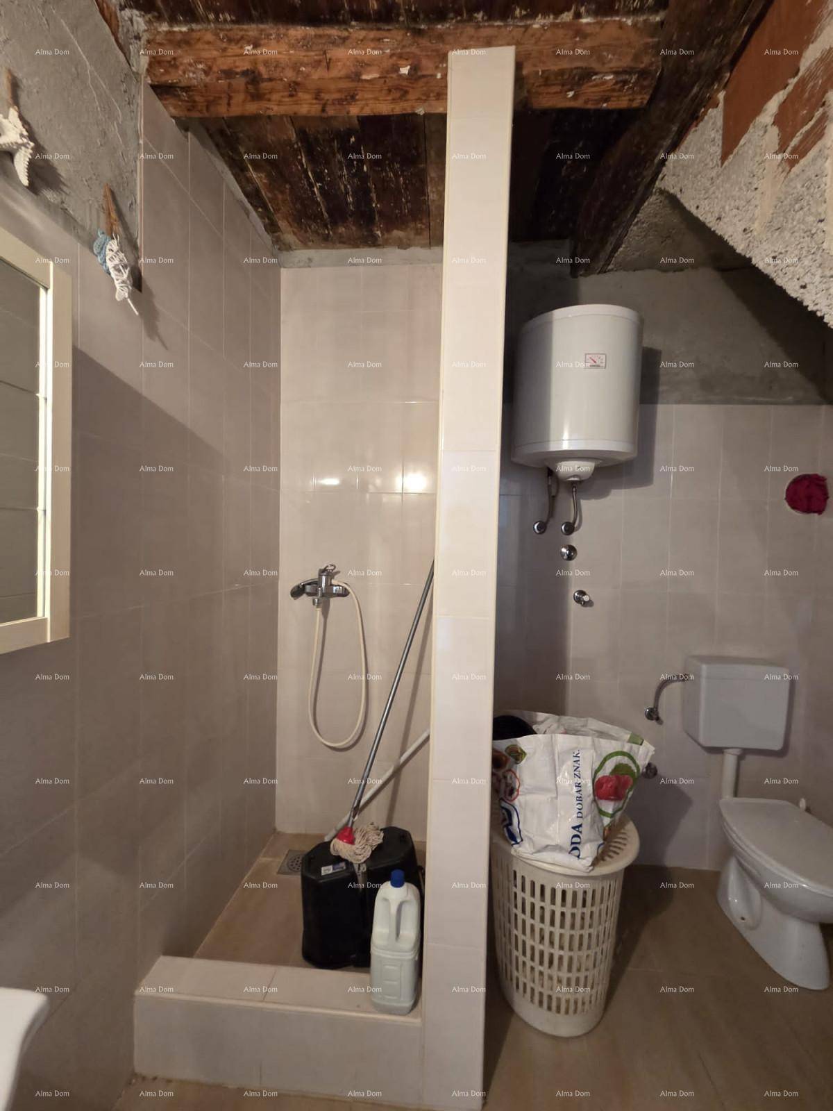 Einfaches Badezimmer mit Duschbereich, Boiler und Toilette unter einer rustikalen Holzdecke.