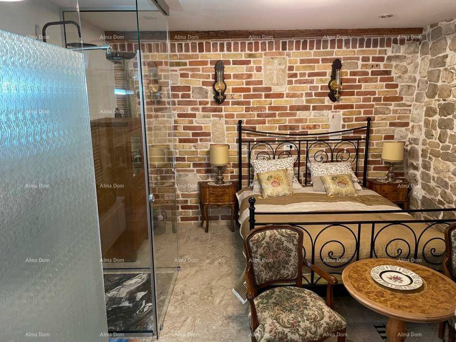 Rustikales Schlafzimmer mit Stein- und Ziegelwänden, schmiedeeisernem Bett und offenem Duschbereich hinter Glas.