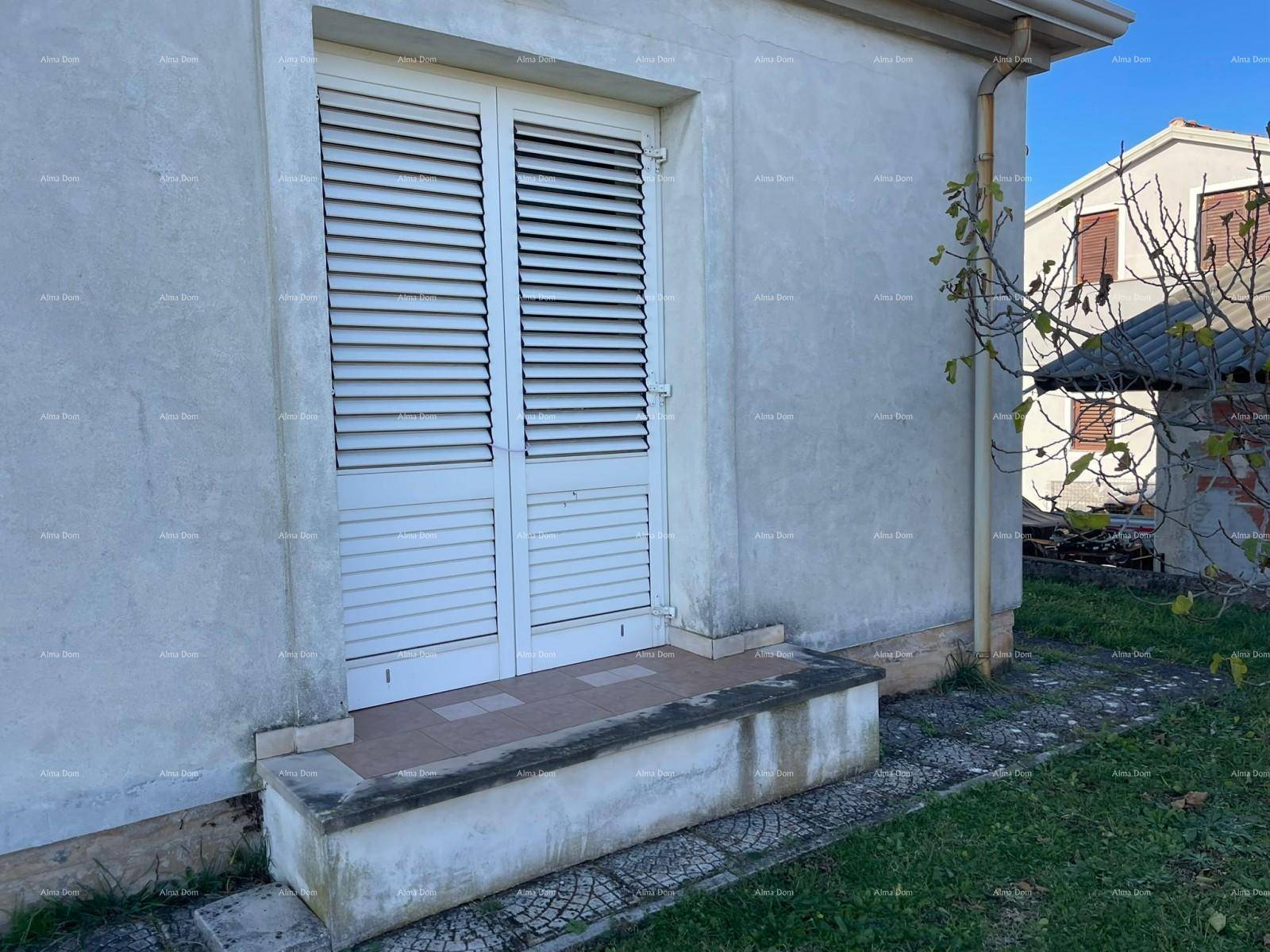 Weiße Fensterläden an einer Außentür des Hauses mit einfacher Fassade und kleinem Podest.