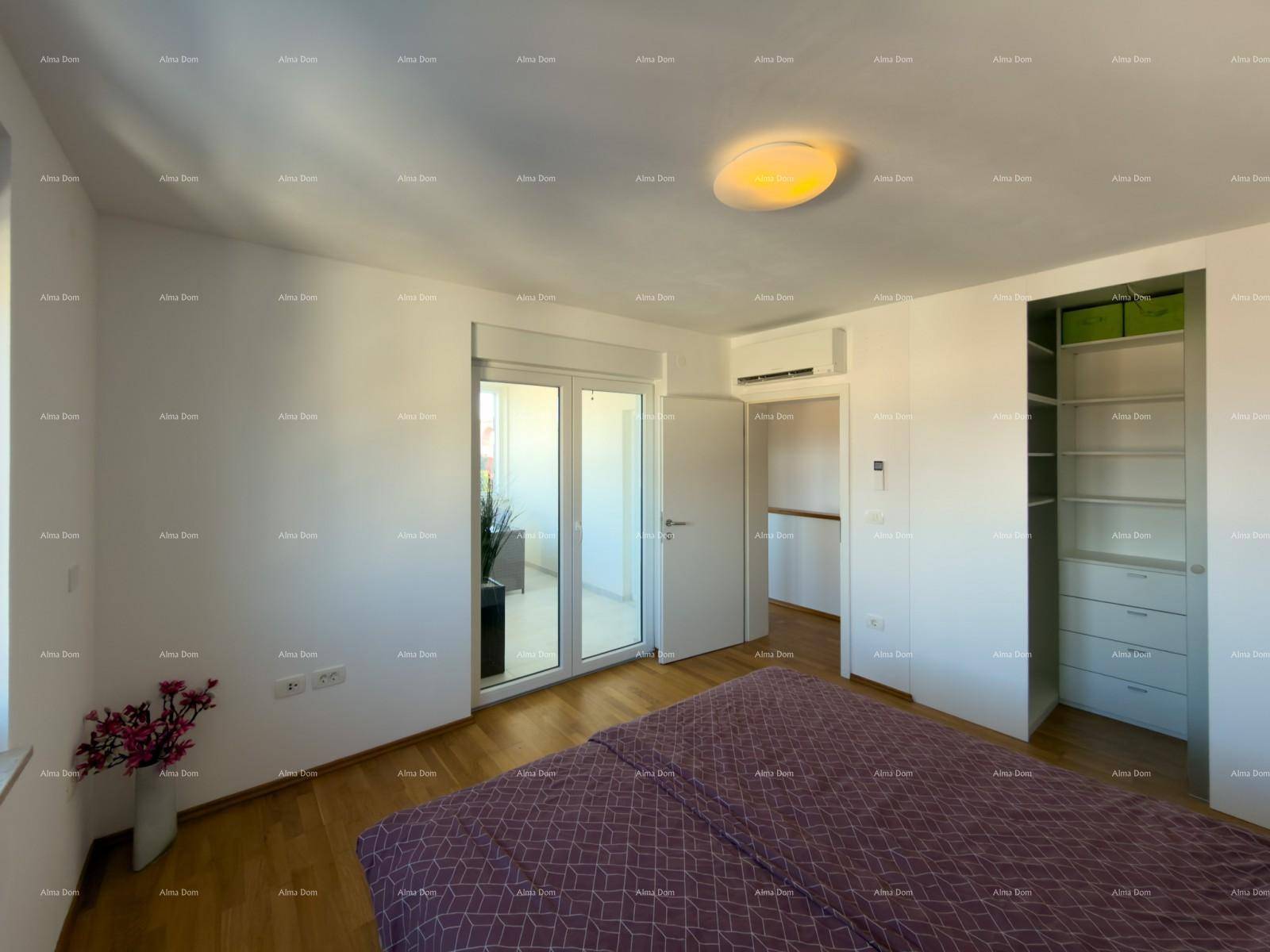 Helles Schlafzimmer mit Holzboden, offenem Kleiderschrank und Zugang zu einem verglasten Balkon.
