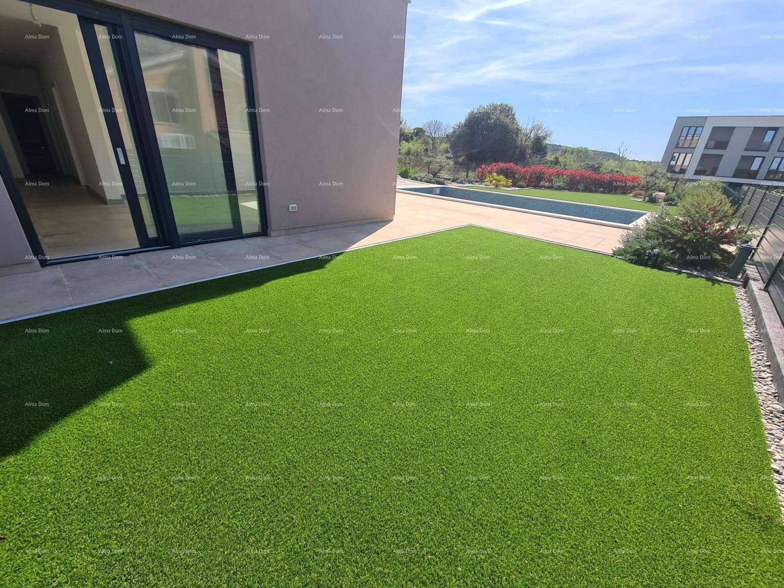 Grüne Rasenfläche neben dem Gebäude mit großen Glasschiebetüren und Blick auf den Poolbereich.