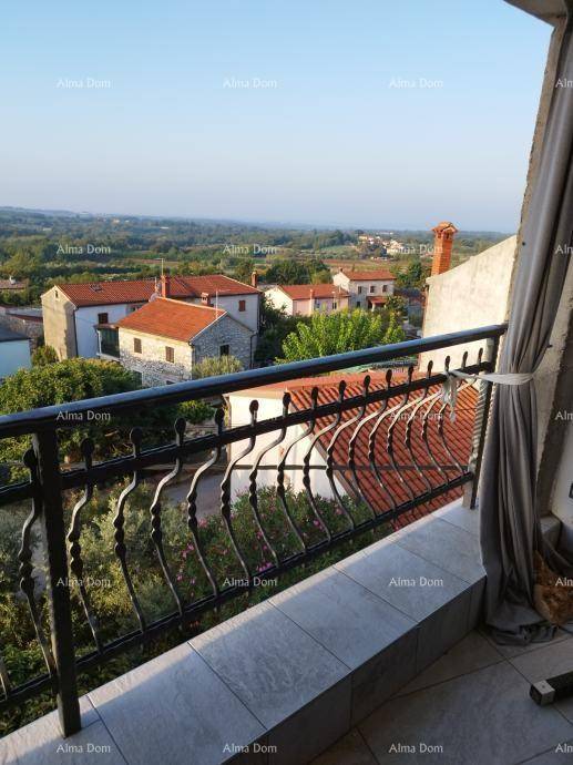 Balkon mit schmiedeeisernem Geländer und einem weiten, grünen Blick über die ländliche Umgebung.