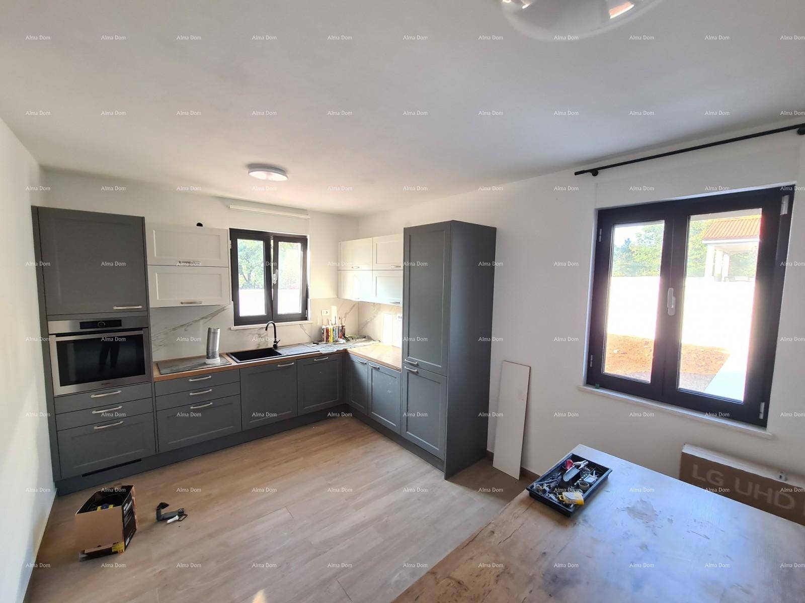 Moderne Küche mit grauen und weißen Schränken, Holzarbeitsplatte und großem Fenster.
