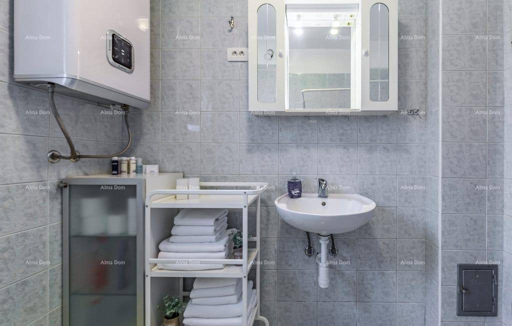 Badezimmer mit Waschbecken, Spiegelschrank und hellblauen Wandfliesen.