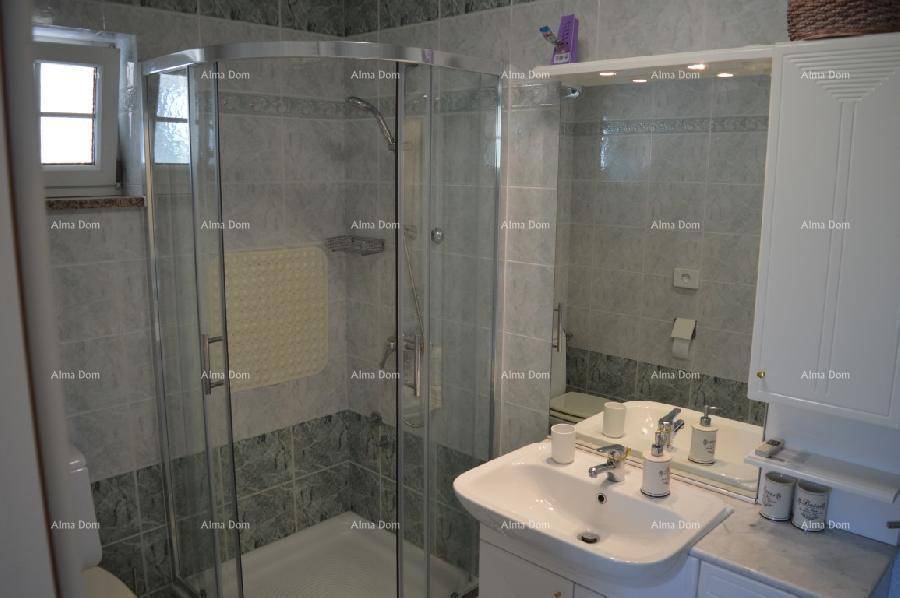 Helles Badezimmer mit Duschkabine, Waschtisch und Fenster, modern gefliest in Grau.