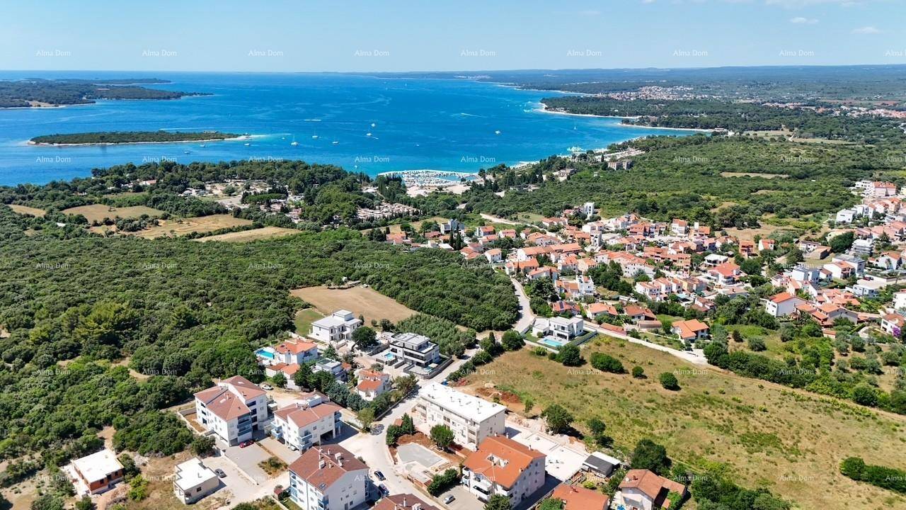 Weitläufige Luftaufnahme einer Küstenlandschaft mit Siedlungen, viel Grün und dem Meer.