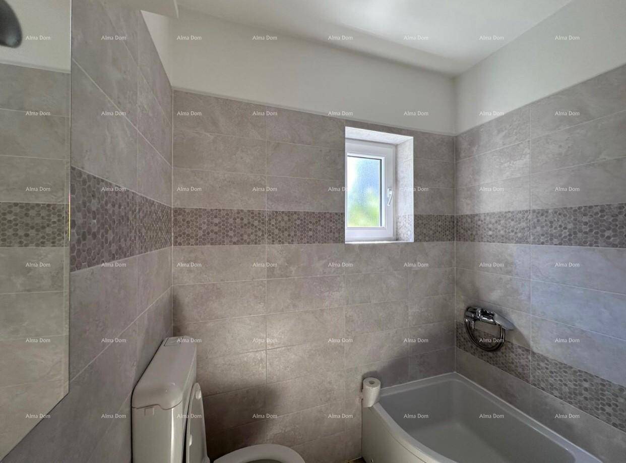 Badezimmer mit Badewanne, Toilette und einem kleinen Fenster, modern gefliest.