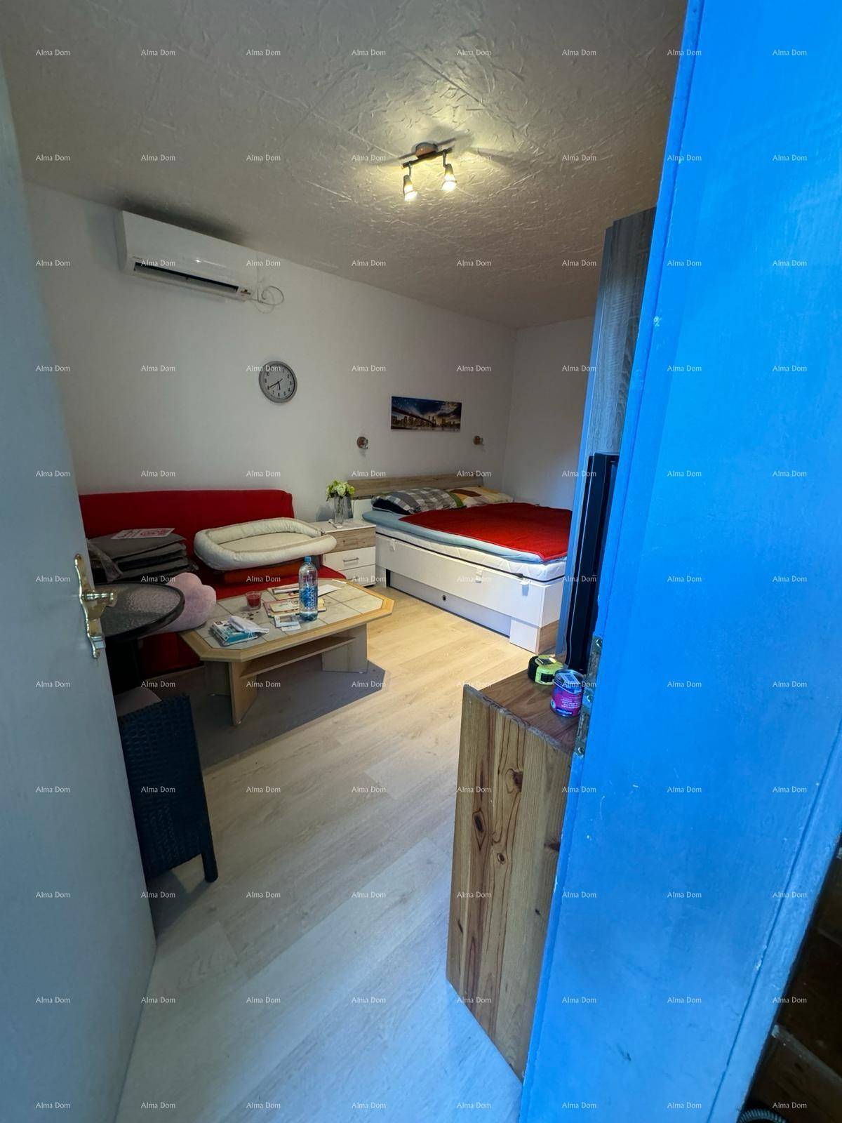 Gemütliches Schlafzimmer mit Doppelbett, kleinem Sofa und Klimaanlage, hell beleuchtet.