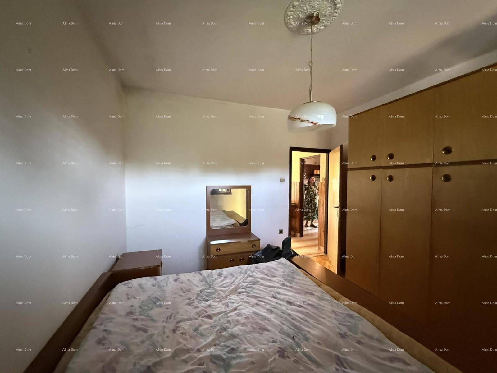 Schlafzimmer mit Bett, Kommode und großem Einbauschrank aus Holz.