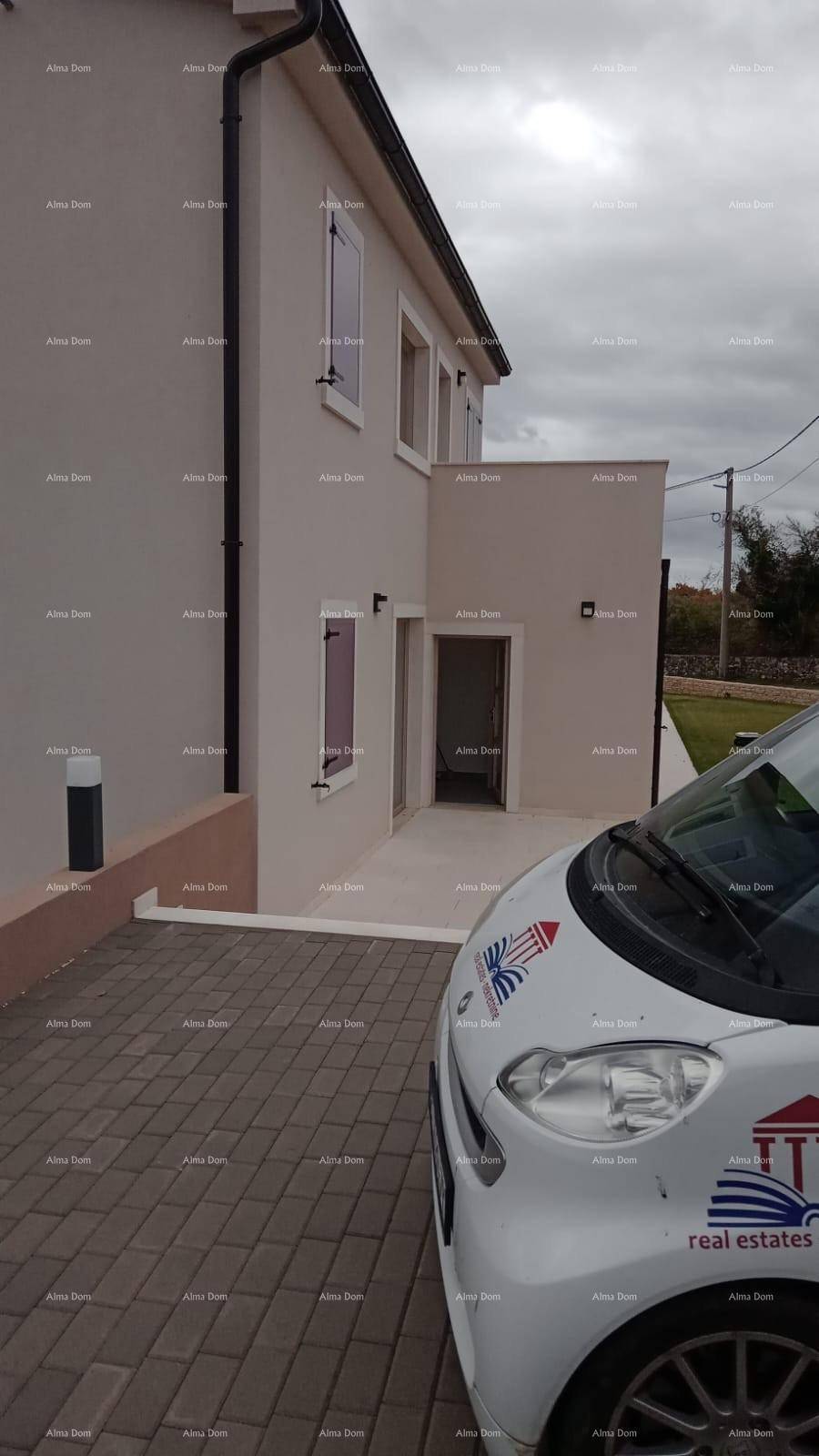 Moderne Hausfassade mit gepflasterter Auffahrt und einem geparkten Kleinwagen.