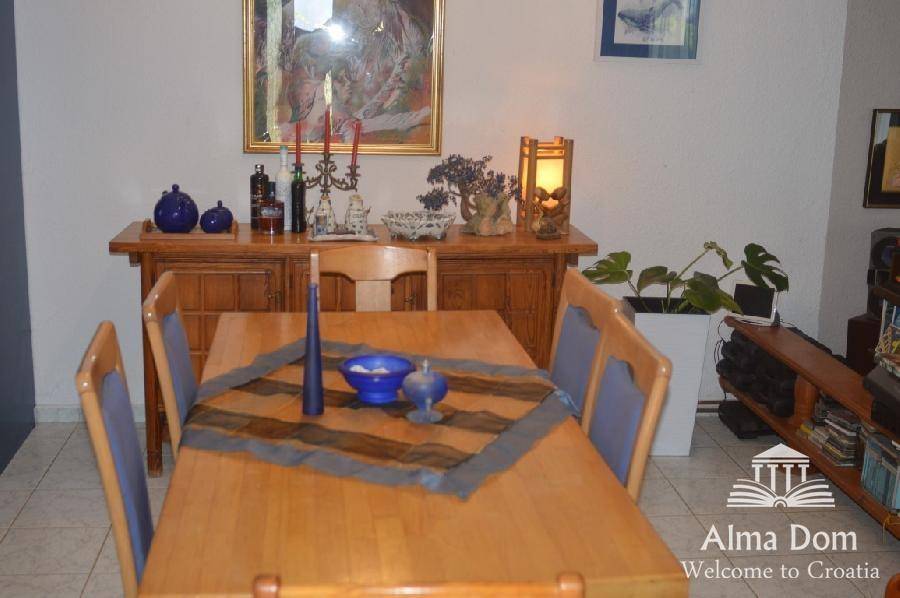 Esszimmer mit Holztisch, passenden Stühlen und einem Sideboard, dekoriert mit Kunst und Pflanzen.