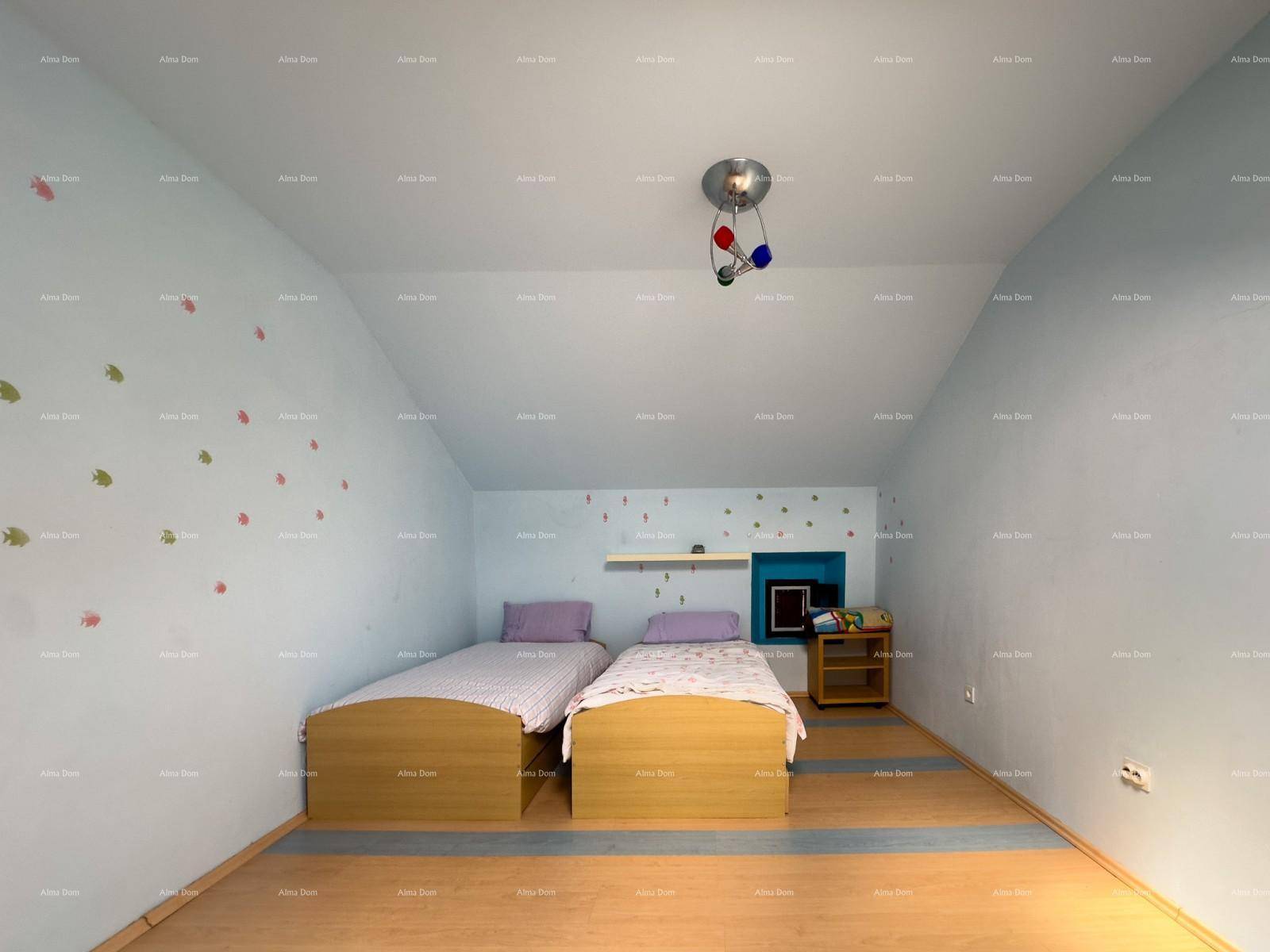 Kinderzimmer im Dachgeschoss mit zwei Einzelbetten, blauen Wänden und Holzboden.