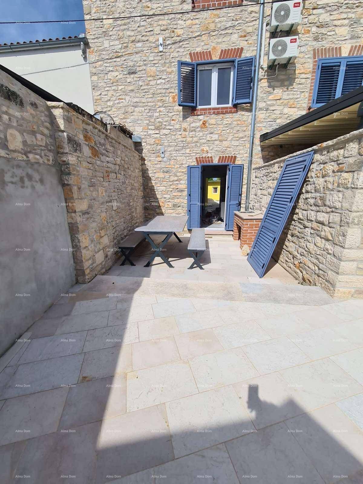 Gemütliche Terrasse mit Steintisch, Bänken und Grill vor der Steinfassade des Hauses.