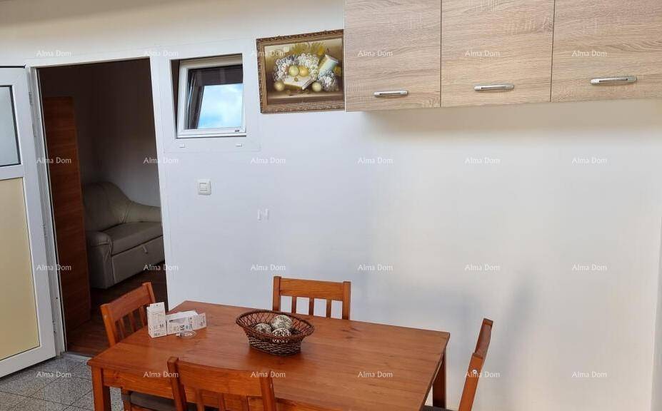 Gemütlicher Essbereich mit Holztisch, Küchenschränken und Blick in einen angrenzenden Raum.