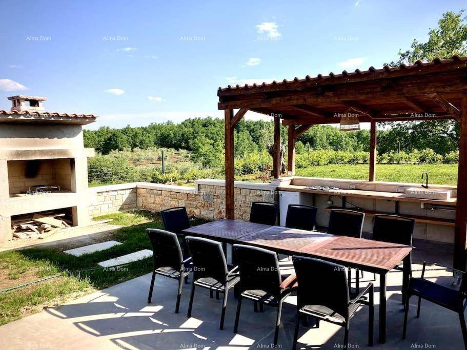 Großer Gartenbereich mit Grillplatz, Esstisch und Pergola, umgeben von viel Grün.