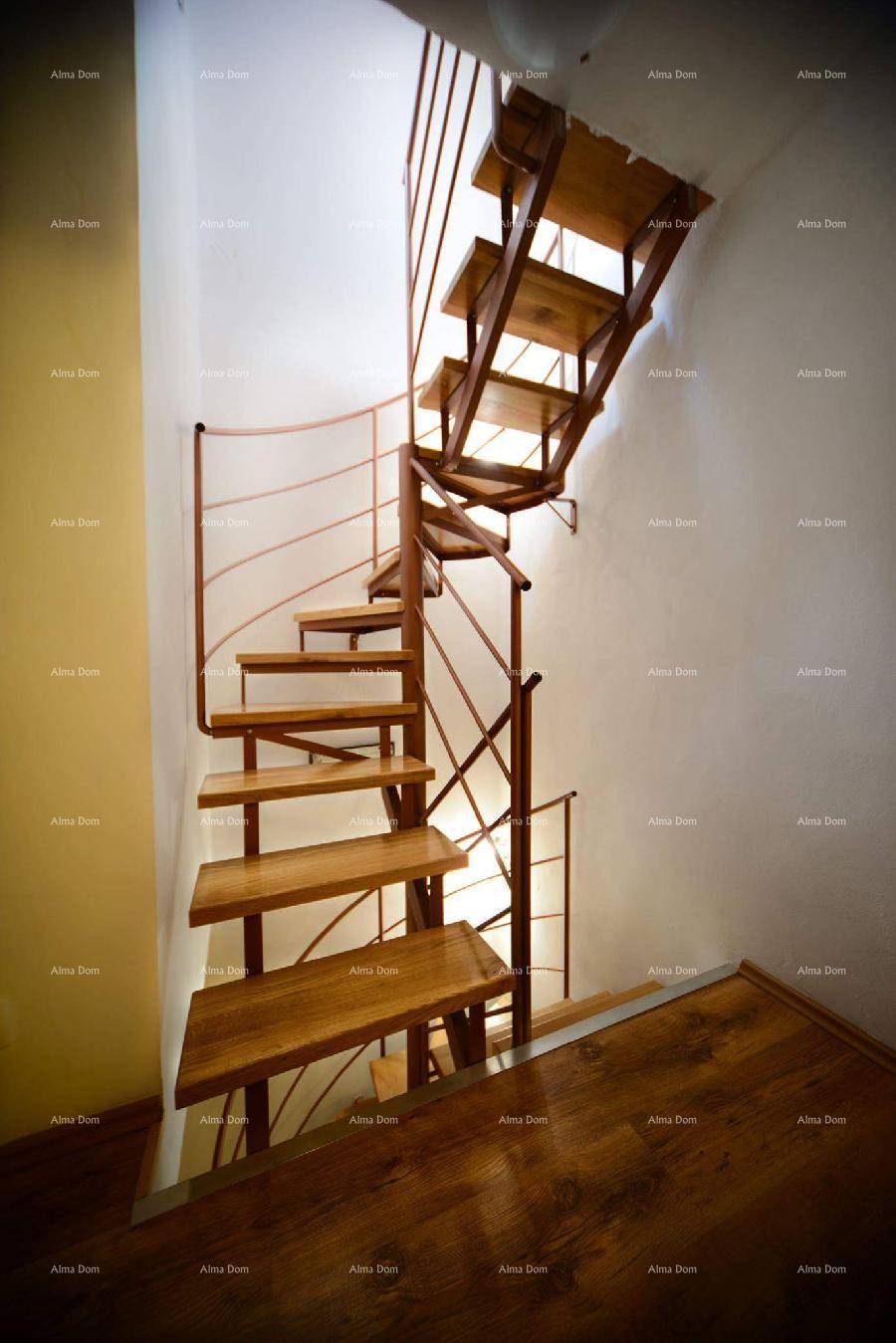 Elegante Holz-Wendeltreppe mit Metallgeländer verbindet die Etagen des Hauses.