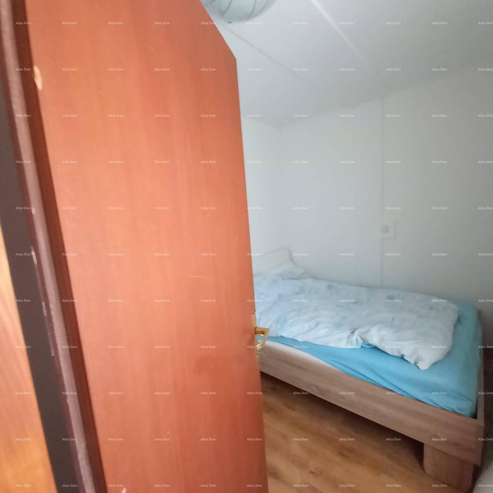 Gemütliches Schlafzimmer mit Holzbett und Laminatboden, durch eine offene Tür sichtbar.