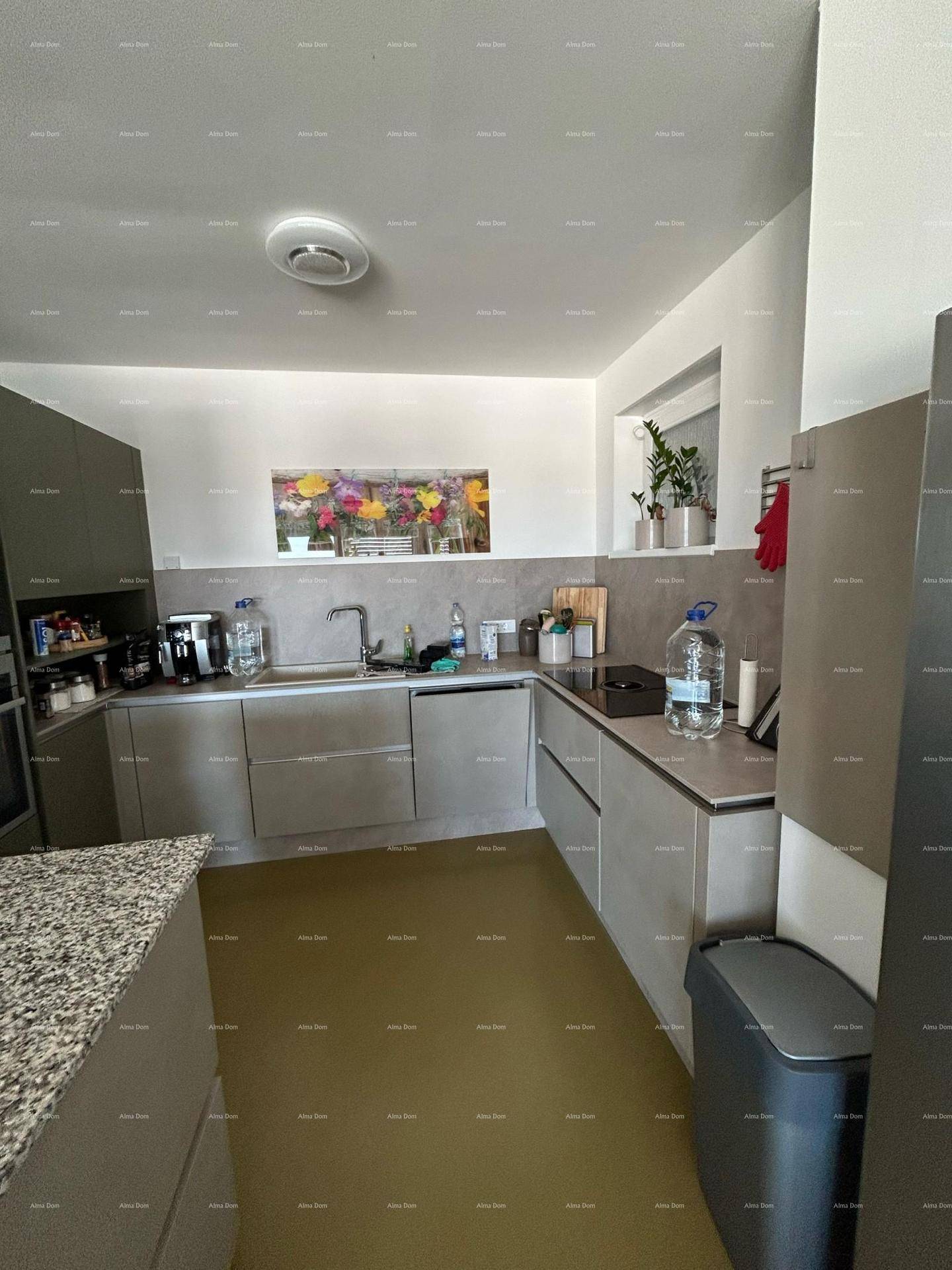 Moderne Küche mit grauen Schränken, integrierten Geräten und einem Fenster.