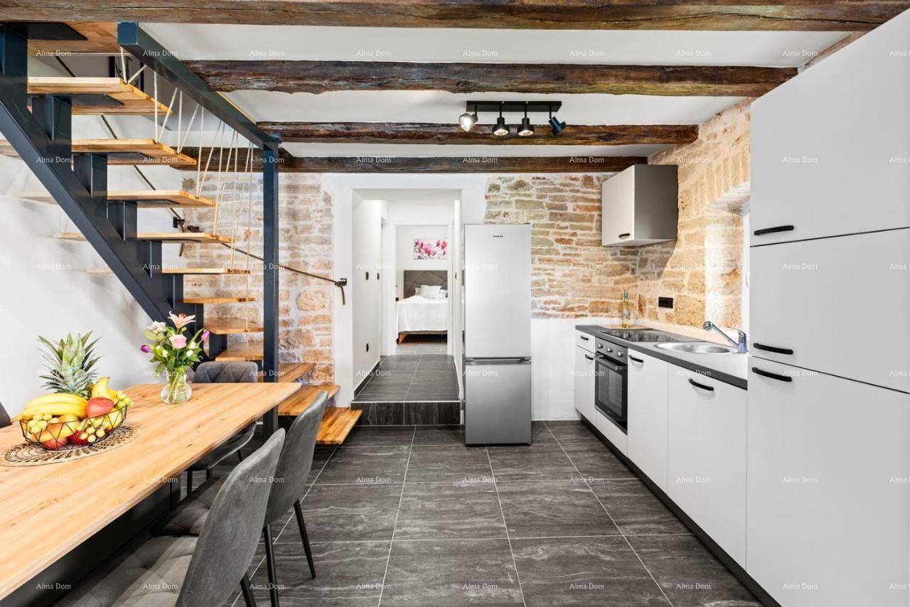 Essbereich mit Holztisch und modernen Stühlen, direkt neben der Küche und einer eleganten offenen Treppe.