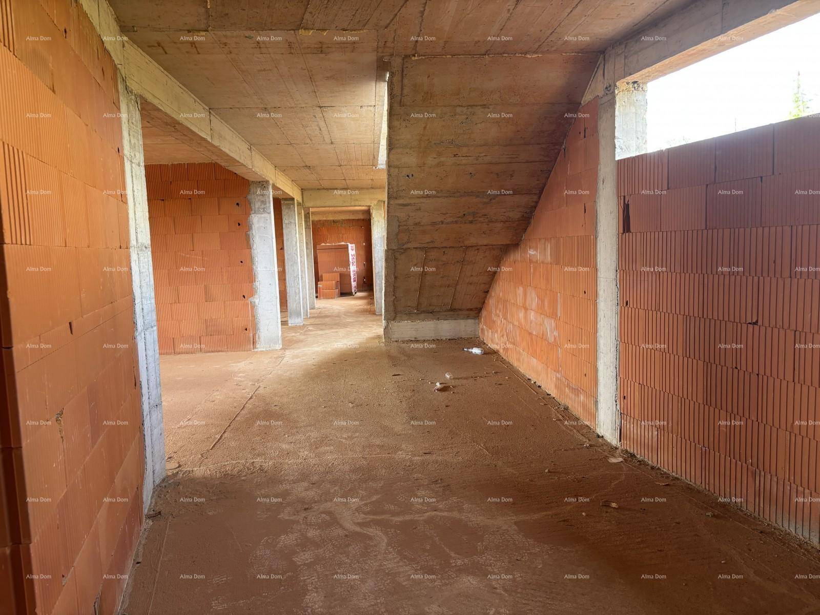 Langer Flur im Rohbau mit sichtbaren Ziegelwänden und Betonstützen, noch im Bauzustand.