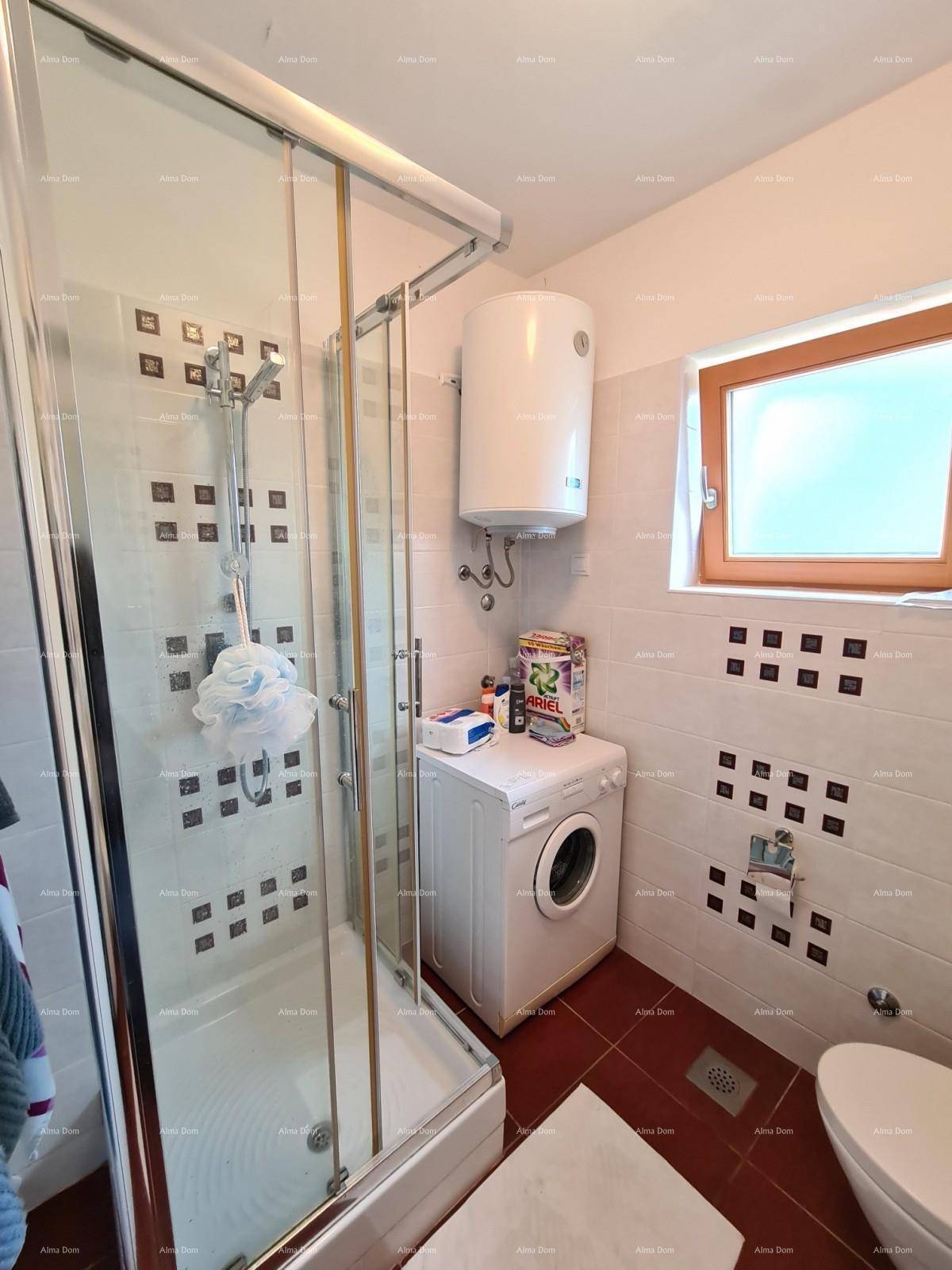 Badezimmer mit Duschkabine, Waschmaschine und Fenster, ausgestattet mit hellen Fliesen.