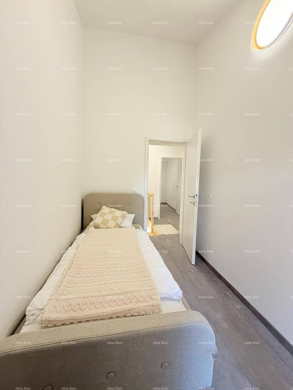 Kleines Schlafzimmer mit Einzelbett, hellem Fliesenboden und Zugang zu einem weiteren Raum.