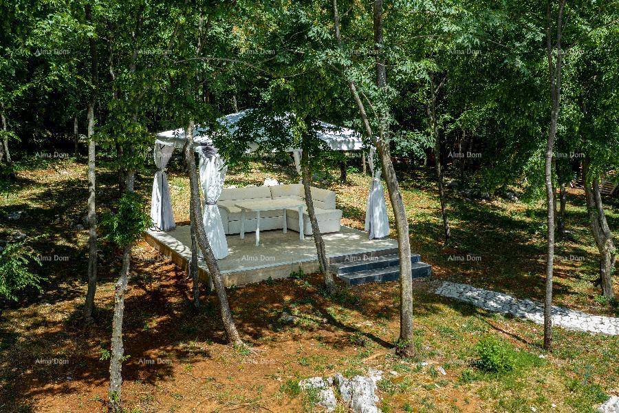 Gemütlicher Outdoor-Loungebereich mit weißen Möbeln unter einem Pavillon, umgeben von Bäumen.