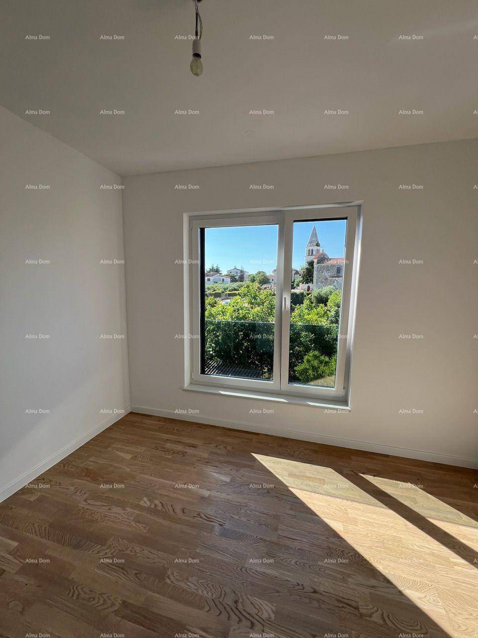 Helles Schlafzimmer mit Holzboden und Fenster mit Blick auf die grüne Umgebung und einen Kirchturm.