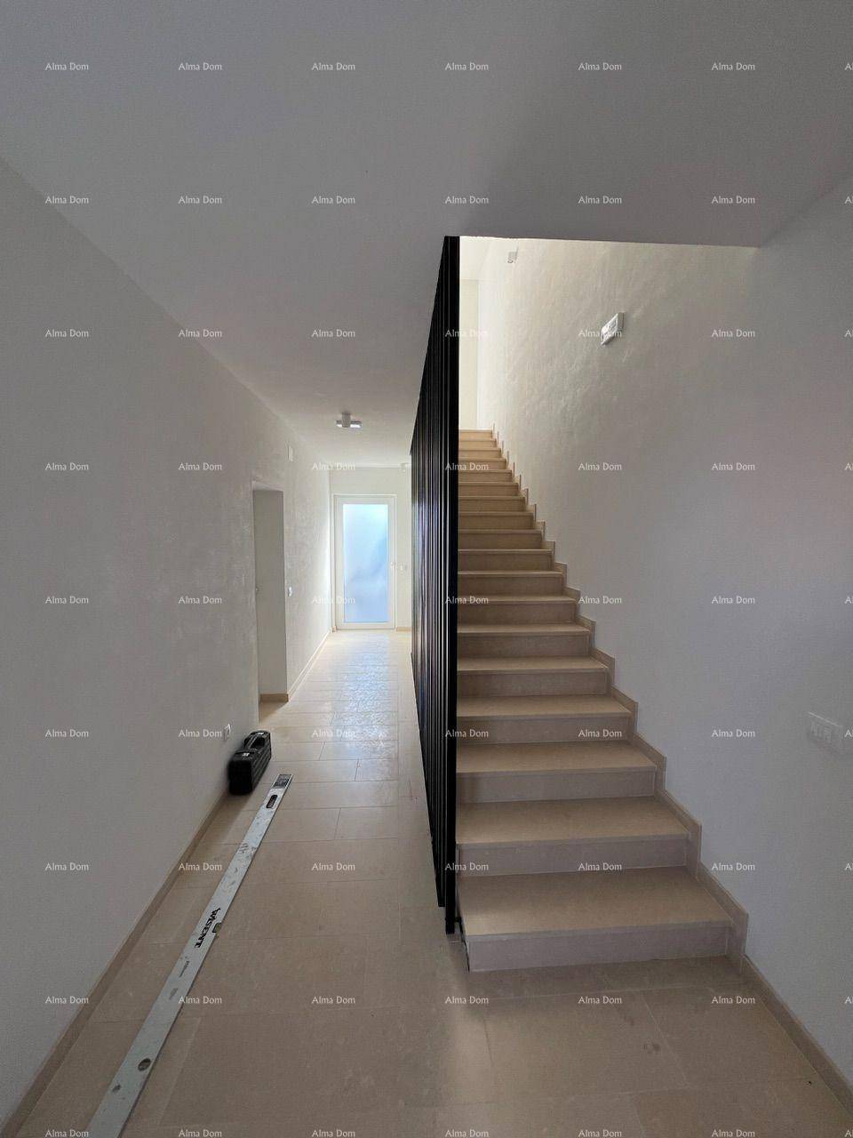 Heller Flur mit moderner Treppe und Fliesenboden, der zu weiteren Räumen führt.