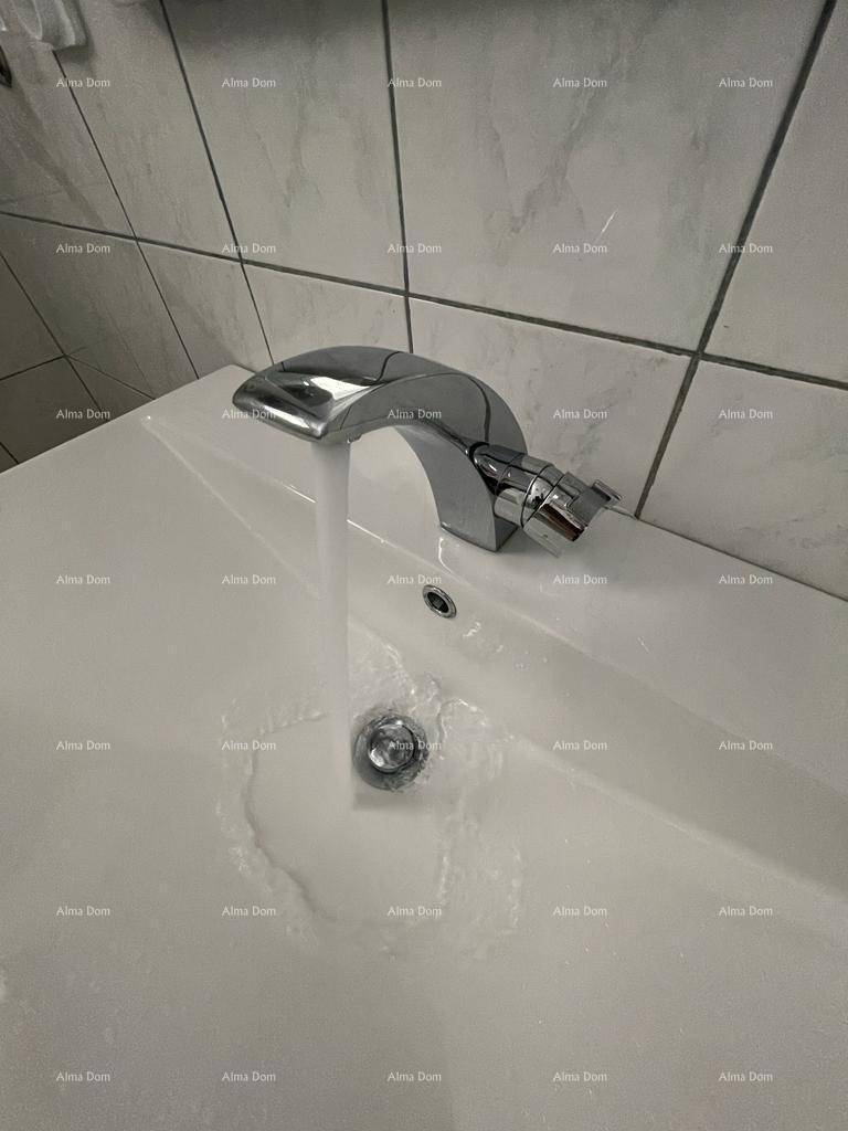Modernes Waschbecken mit Chromarmatur und fließendem Wasser in einem gefliesten Badezimmer.