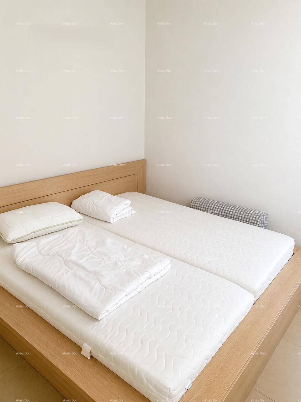 Helles Schlafzimmer mit zwei Einzelmatratzen in einem Holzrahmenbett, ideal für Gäste oder Kinder.