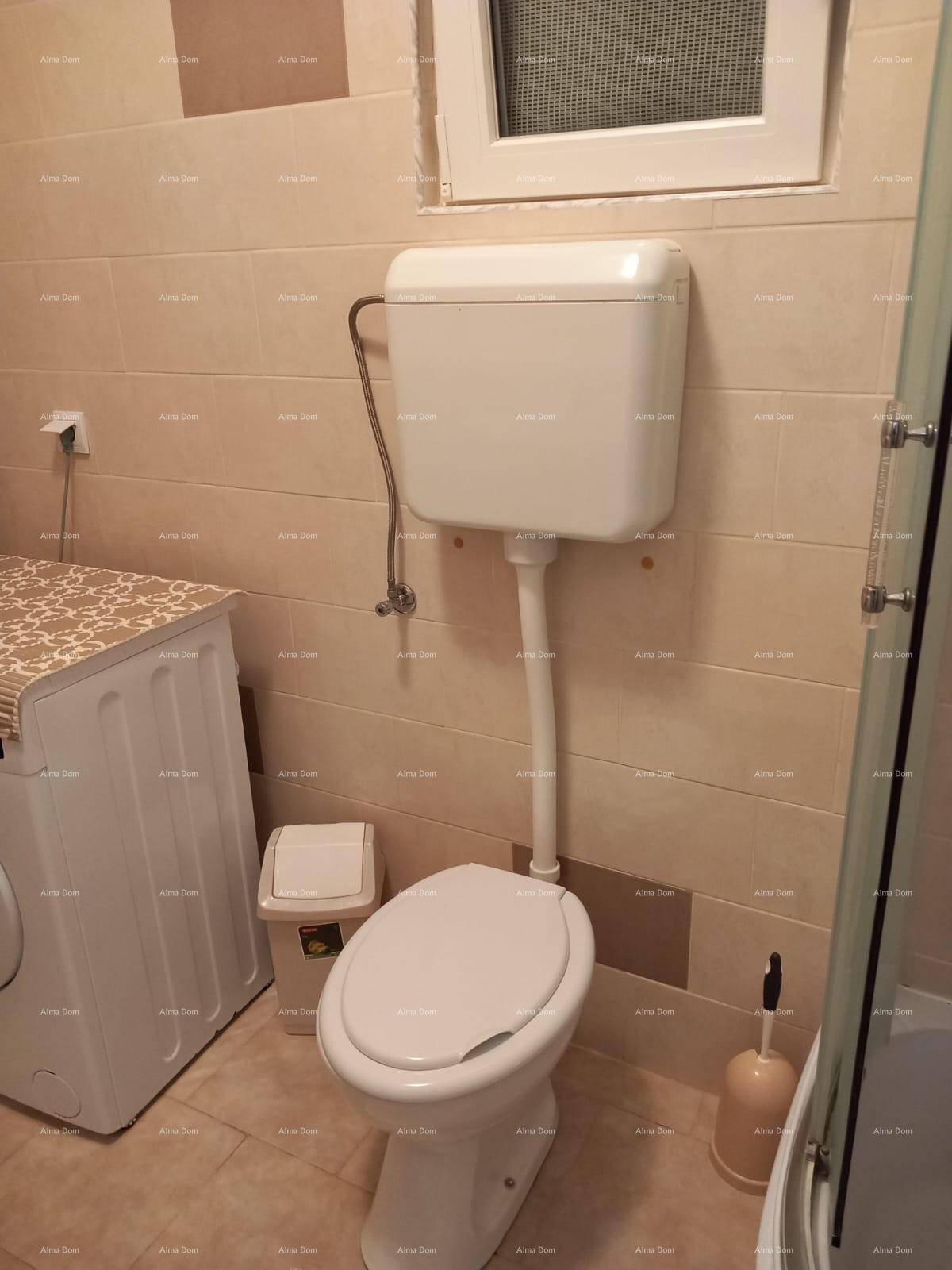 Badezimmer mit Toilette, Waschmaschine und beigefarbenen Fliesen, funktional eingerichtet.