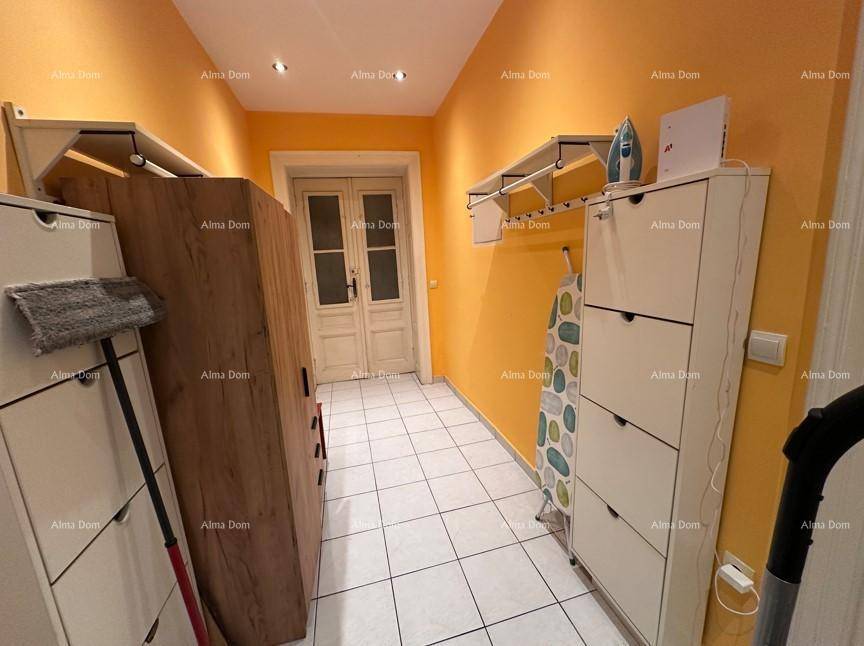 Schmaler Flur mit orangefarbenen Wänden, weißen Fliesen und praktischen Schuhschränken.