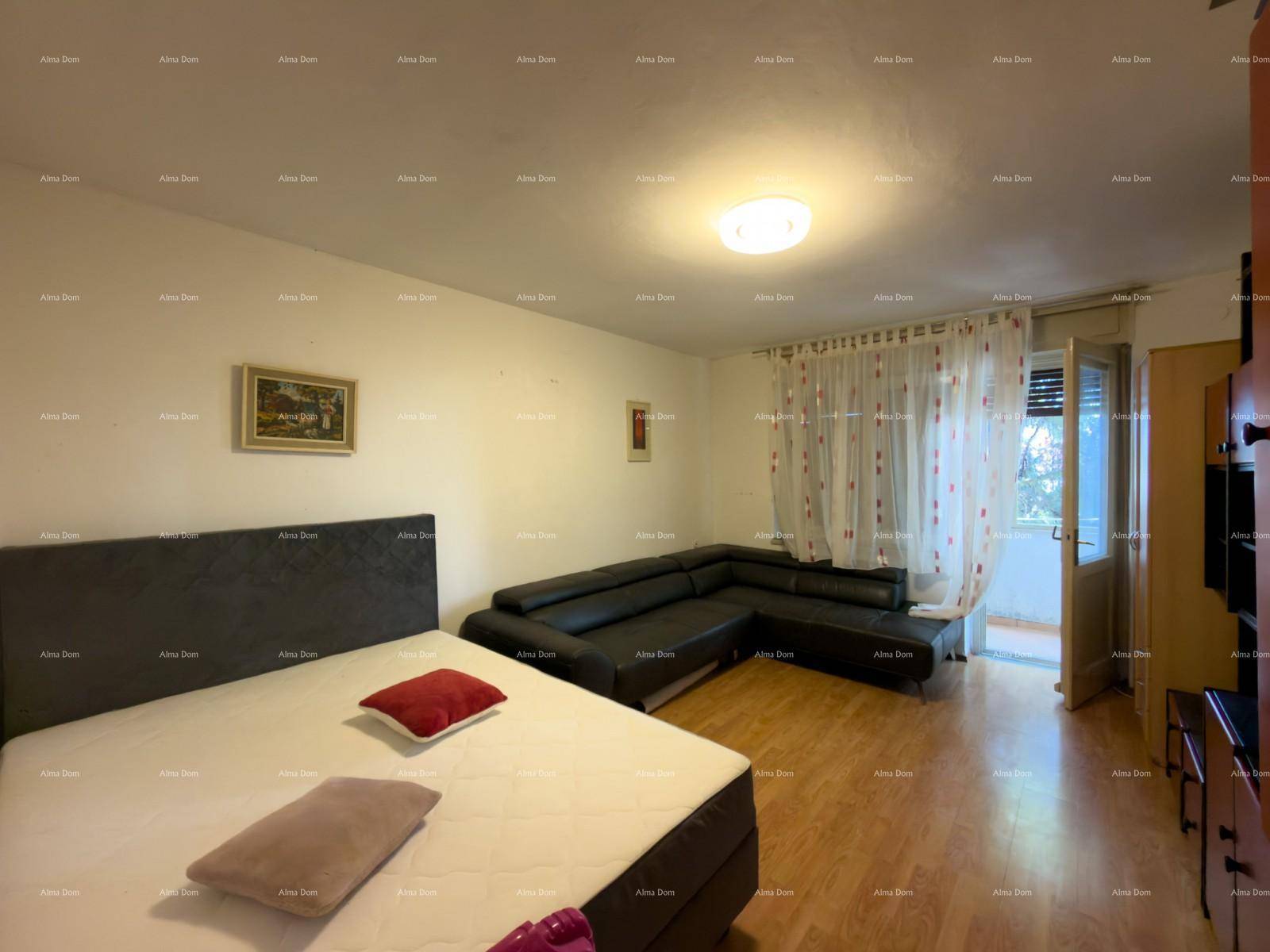Schlafzimmer mit Bett, Sofa, Holzfußboden und Zugang zum Balkon.