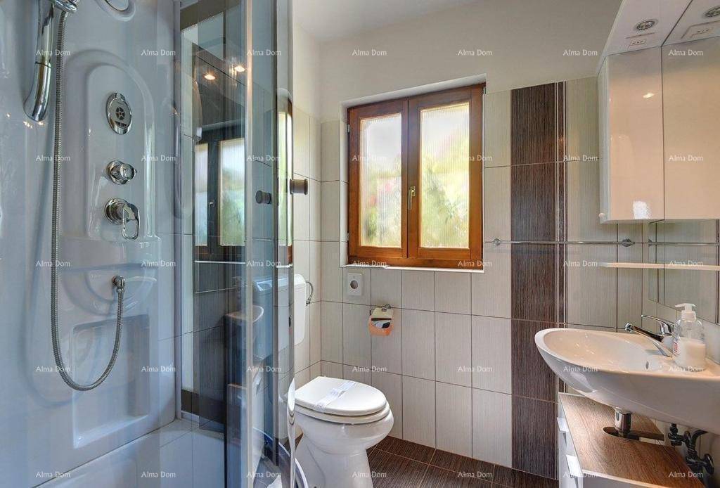 Badezimmer mit Duschkabine, WC, Waschbecken und Fenster.