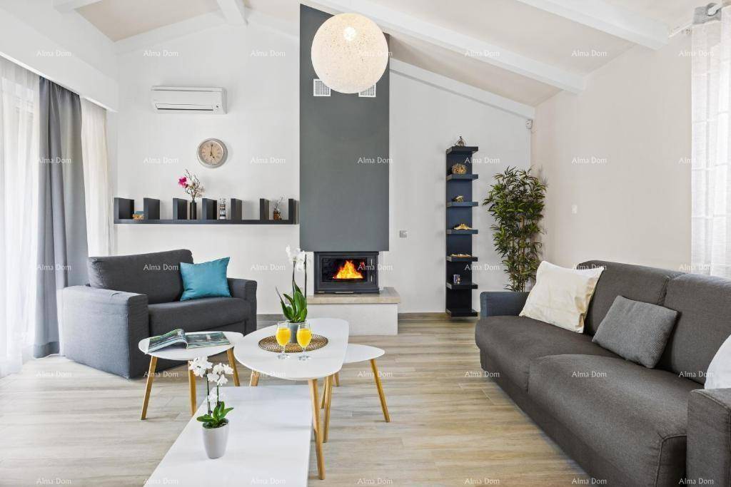 Helles Wohnzimmer mit Kamin, hohen Decken und modernen Möbeln in Grautönen.