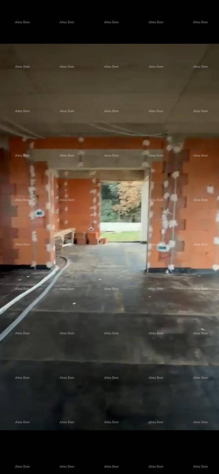 Unfertiger Innenraum im Rohbau mit offener Türöffnung und Blick ins Grüne.