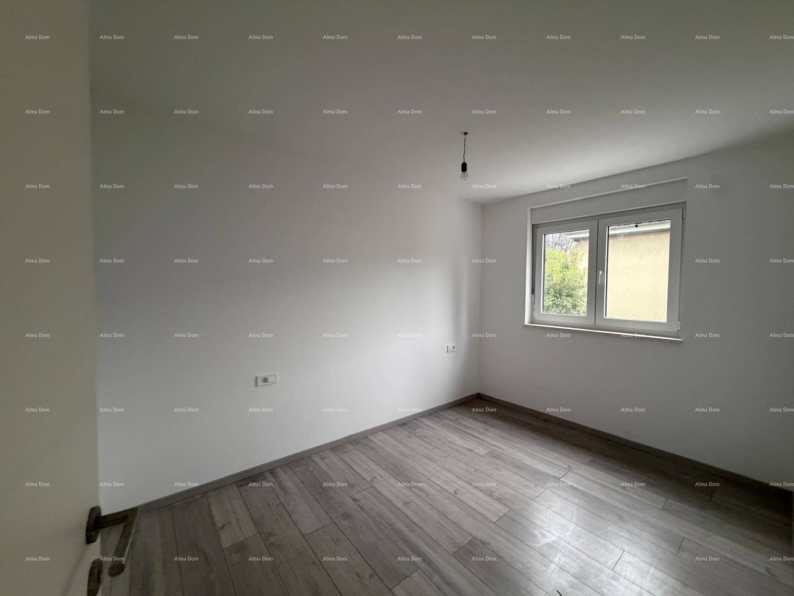 Unfertiges Schlafzimmer mit Laminatboden und einem Fenster, das Tageslicht hereinlässt.