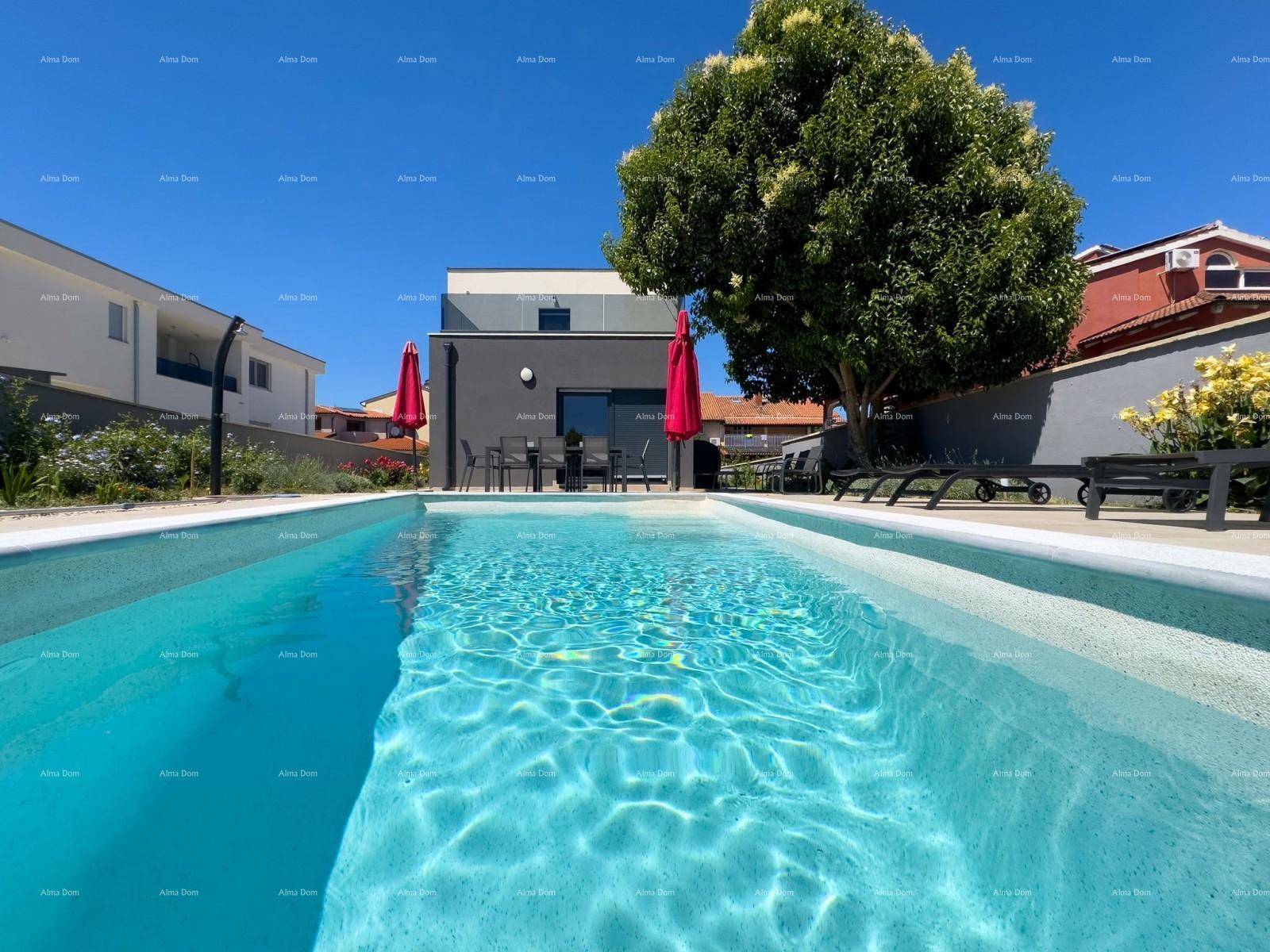 Blick über das klare Poolwasser auf die moderne Villa und den Essbereich im Freien.