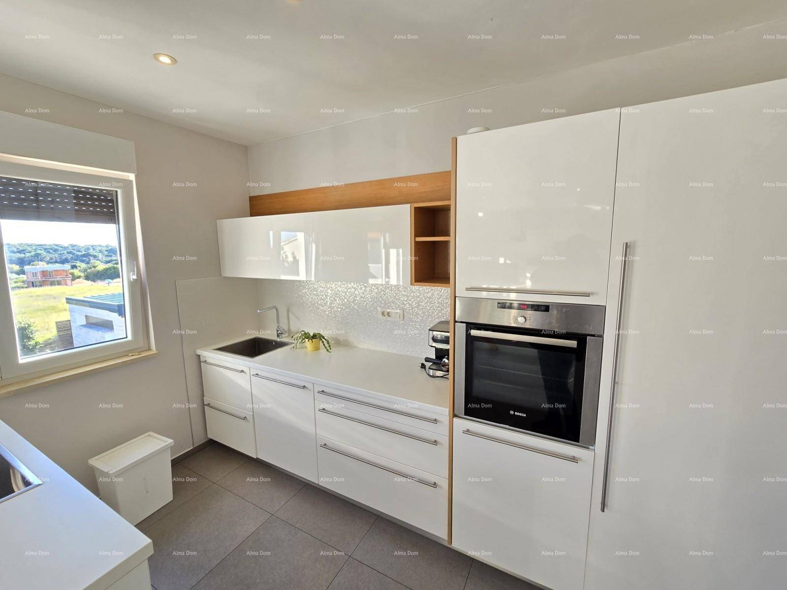 Moderne Küche mit weißen Hochglanzfronten, integriertem Backofen und Fenster.